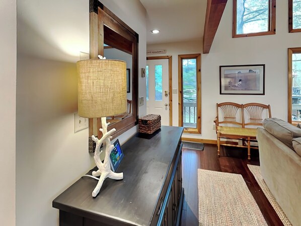 A modern living room with a dark wooden coffee table, a woven lamp, a digital clock, and a framed picture on the wall.