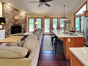 A modern kitchen with a stone accent wall, a built-in oven, and a large island with bar stools. - Somewhere by Taylor Made Deep Creek (Oakland)