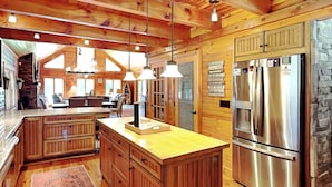 A spacious kitchen with wooden cabinets, a large island, and stainless steel appliances. - Crow's Point Lakehouse by Taylor Made Deep Creek (Swanton)