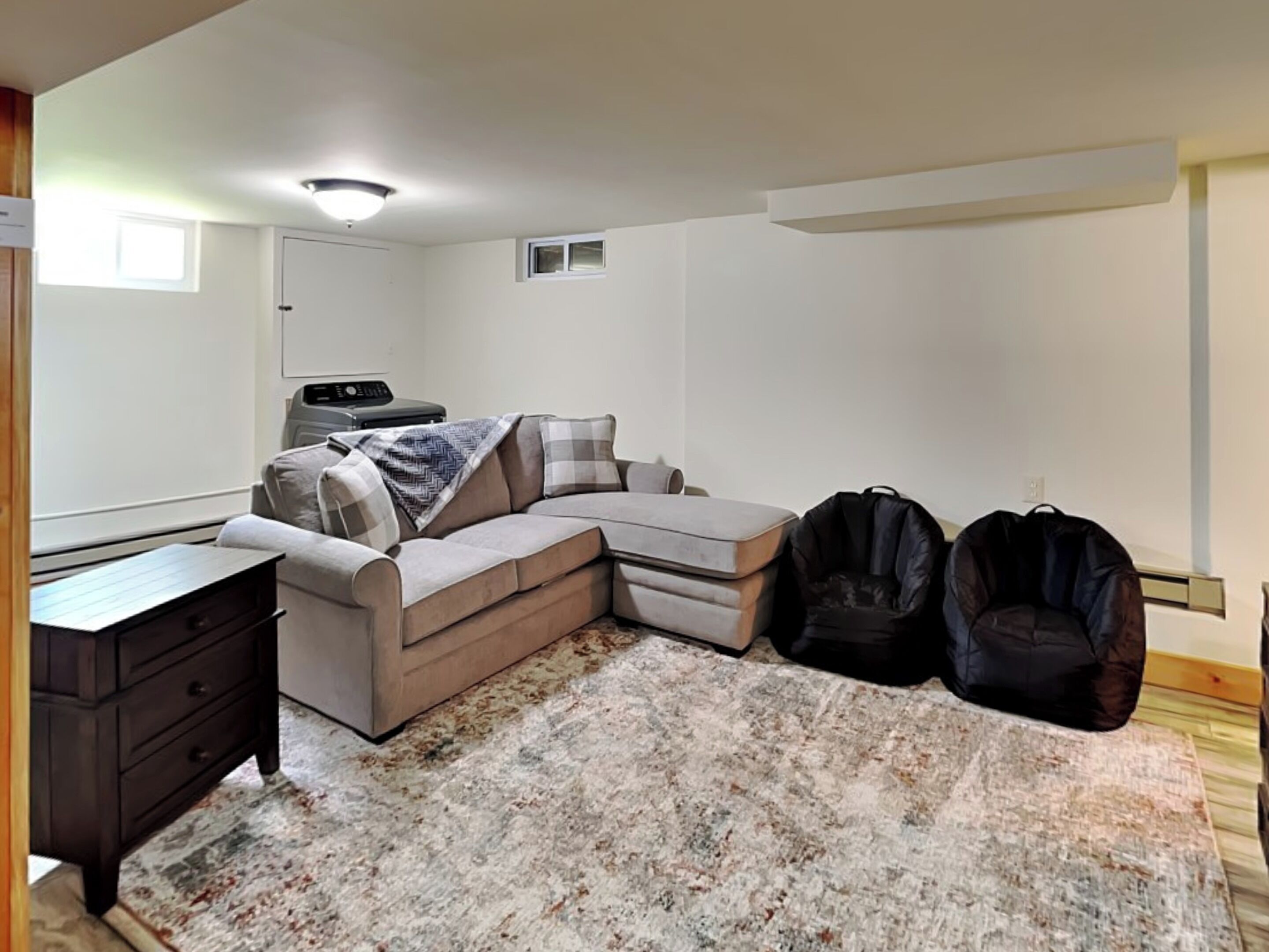 A compact living space with a sectional sofa, a small desk, and a rug.