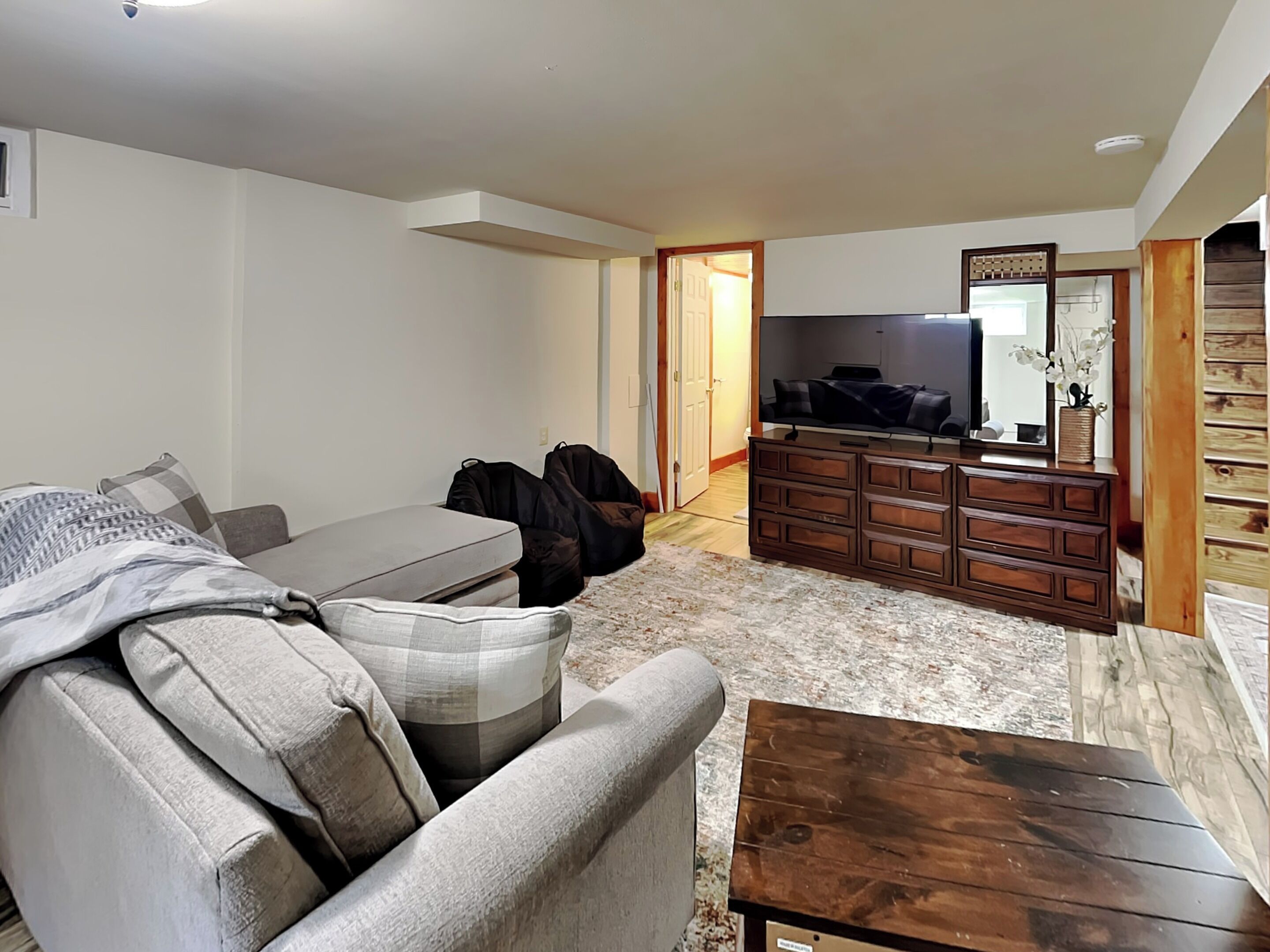 A living room with a sofa, a coffee table, a TV, and a wooden dresser.
