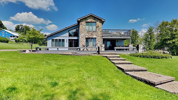 A modern two-story house with a stone facade, large windows, and a balcony.