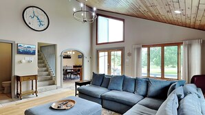 A spacious living room with a large sectional sofa, a wooden ceiling, and a dining area visible through an archway.