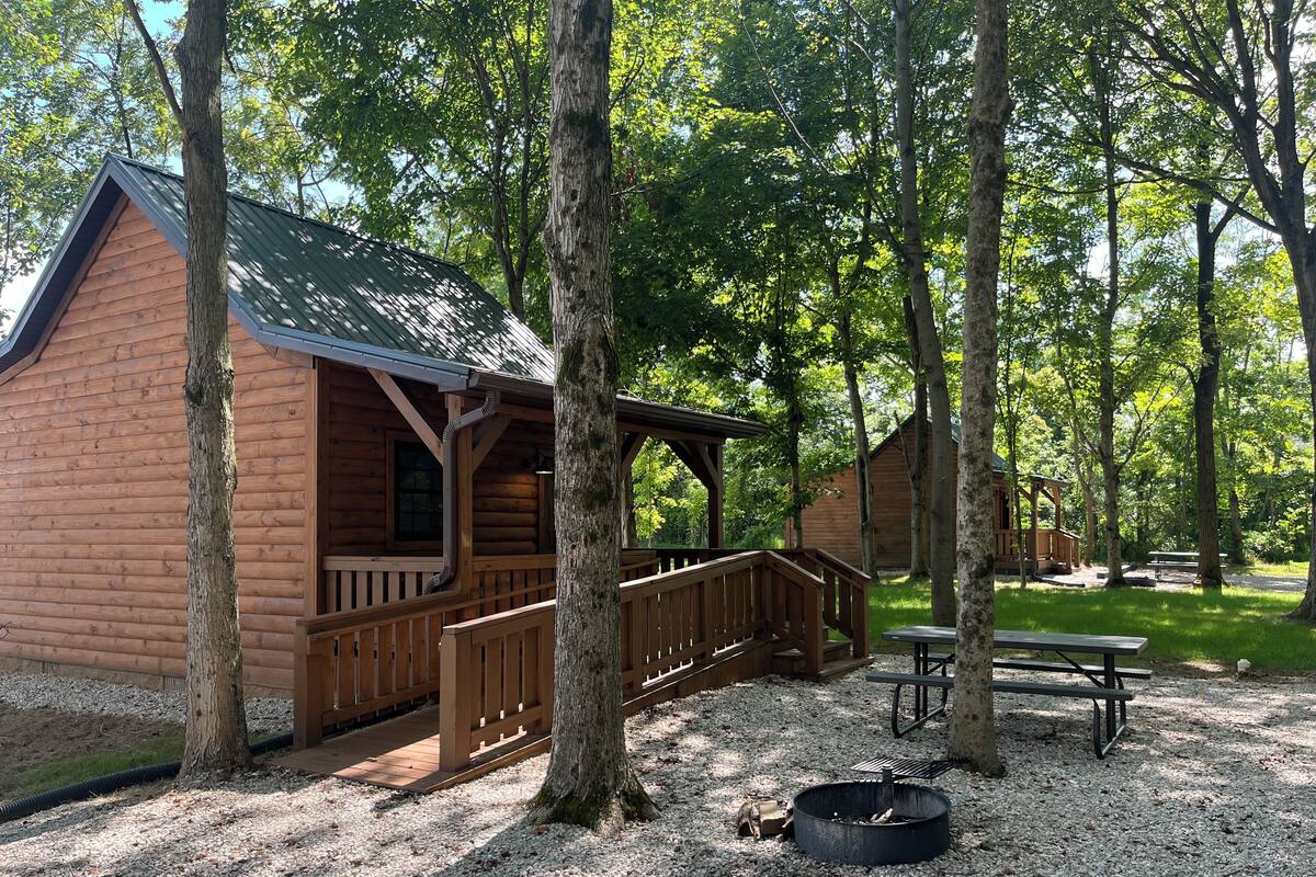 A wooden cabin with a porch and a fire pit.