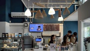 A coffee shop interior with a counter, menu boards, and hanging light fixtures. - Belivin'98 Sense of Pier Sathon Residence (Bangkok)