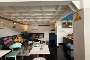 Un café chaleureux avec des tables et des chaises, un comptoir où est affiché le menu, et une enseigne sur laquelle on peut lire « belving98 ».