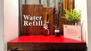 A water refill station with a wooden sign, a faucet, and a potted plant. - Belivin'98 Sense of Pier Sathon Residence (Bangkok)