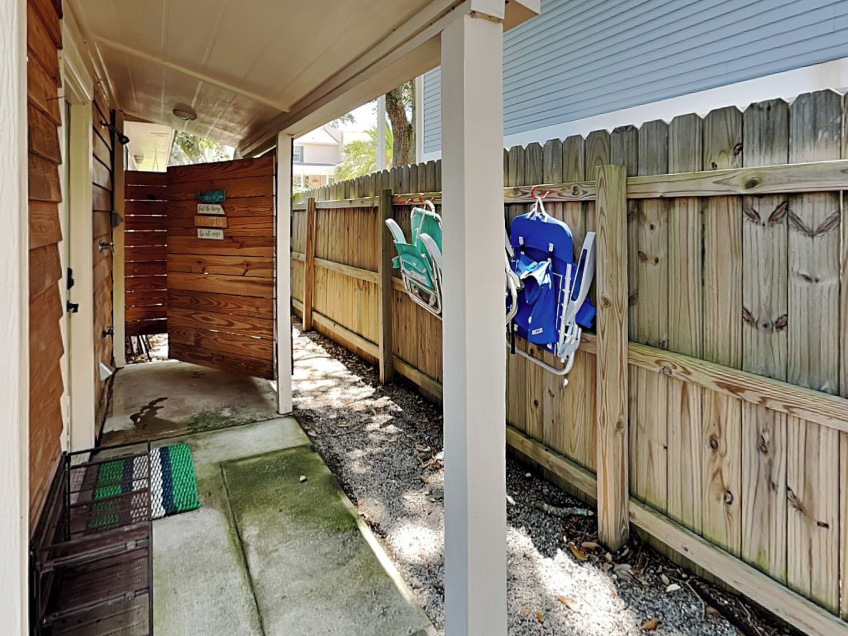 A covered outdoor area with a wooden fence, a green mat, and a blue chair.