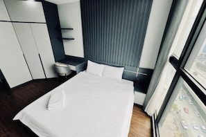 A hotel room with a bed, a desk, and a window with curtains.