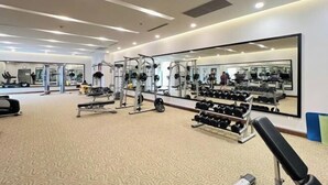 A gym with exercise equipment, a large mirror, and a patterned carpet. - Vinhomes Skylake Ha Noi Services Apartments - GalaxyHouse (Hanoi)