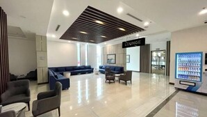 A modern lounge area with a blue sofa, armchairs, and a vending machine. - Vinhomes Skylake Ha Noi Services Apartments - GalaxyHouse (Hanoi)