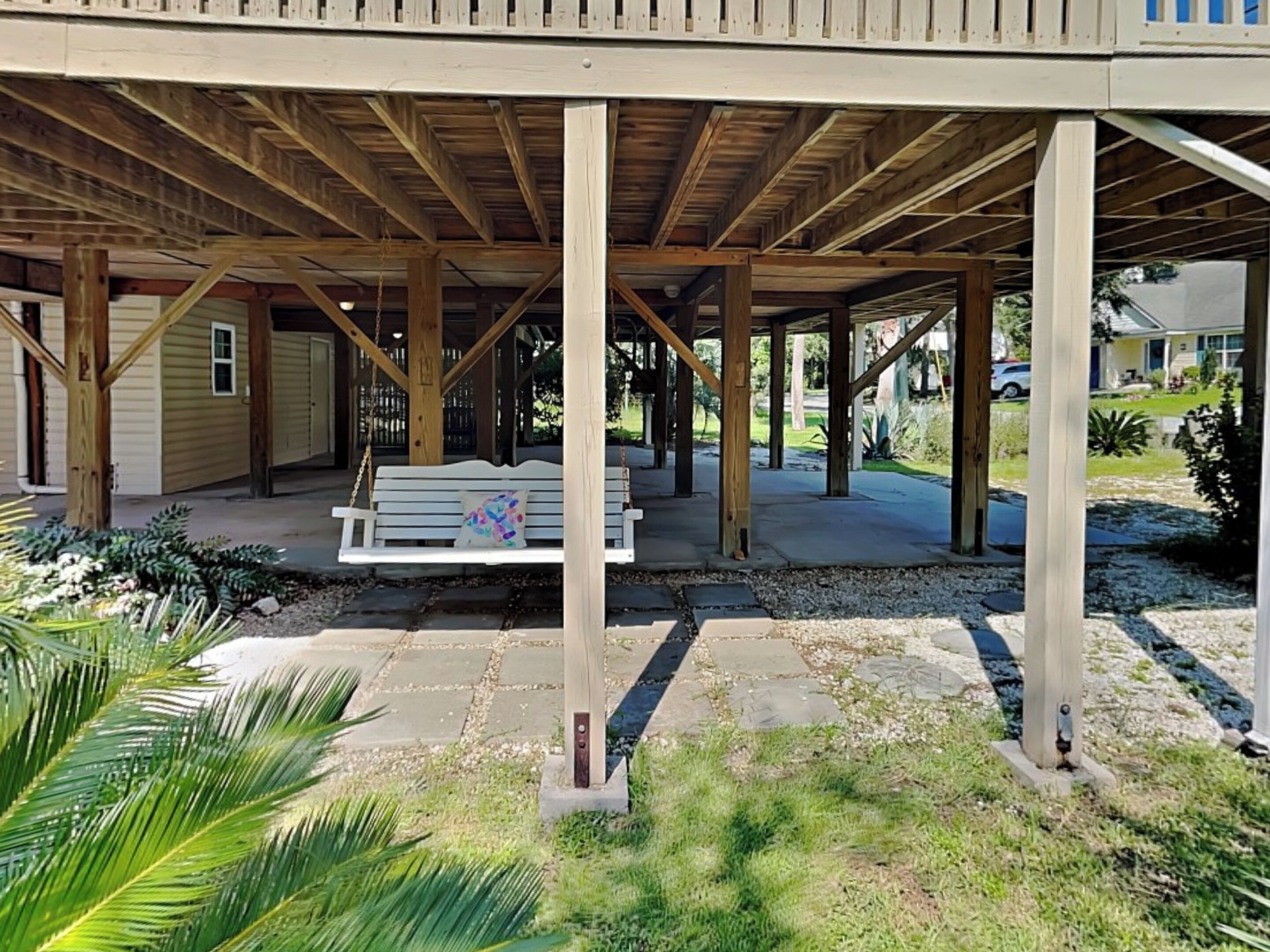 Un patio techado al aire libre con un banco de madera y una mecedora.