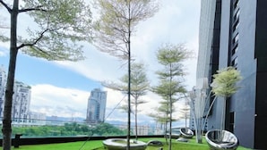A rooftop garden with trees, green grass, and modern metallic seating. - Arte Mont Kiara By Yan Yee (Kuala Lumpur)