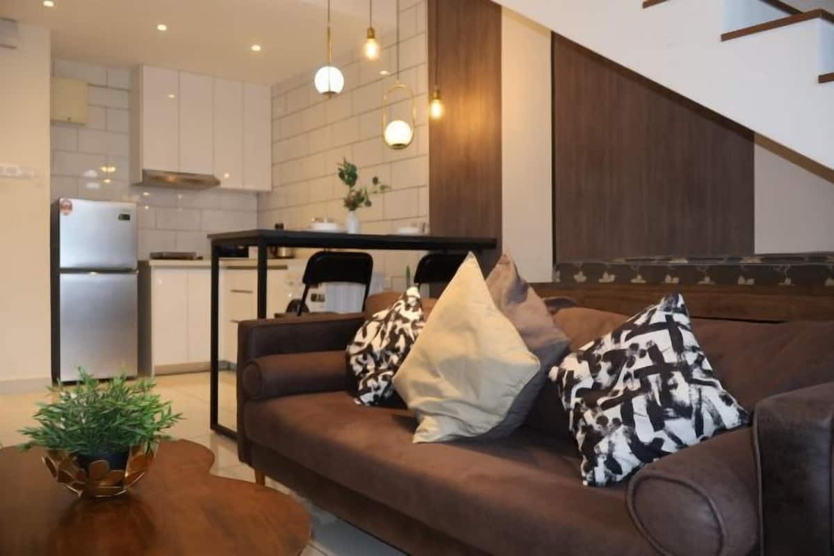 Een moderne woonkamer met een bruine bank, een bijzettafeltje en een eethoek met een tafel en stoelen.