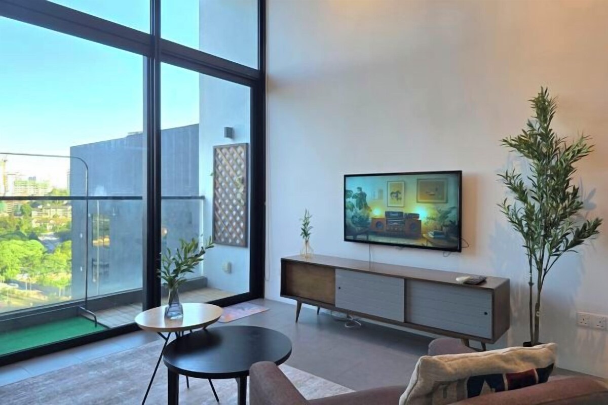 Una sala moderna con un ventanal grande, un televisor de pantalla plana en la pared, un sofá, una mesa de centro y una mesita auxiliar.