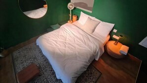 A neatly made bed with white bedding, a round mirror on the wall, and a bedside lamp. - The Establishment Menara Teguh Bangsar Menara UOA KL Sentral (Kuala Lumpur)
