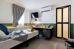 A hotel room with a bed, desk, TV, air conditioning unit, and a sliding door. - Upstairs Downstairs CoLiving Bukit Bintang (Kuala Lumpur)