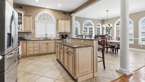 Una cocina amplia con una isla grande, armarios color beige y un comedor con mesa y sillas.