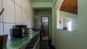 A narrow kitchen with a green countertop, a toaster, and a microwave. A window with a view of the outside is visible.