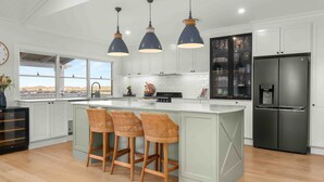 A modern kitchen with a large island, bar stools, pendant lighting, and a view through the windows. - 4BDR, Fireplace, Pool & Pet friendly (Milton)