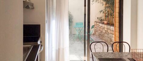 A dining area with a table and chairs, a sliding glass door leading to an outdoor space with a chair and plants.