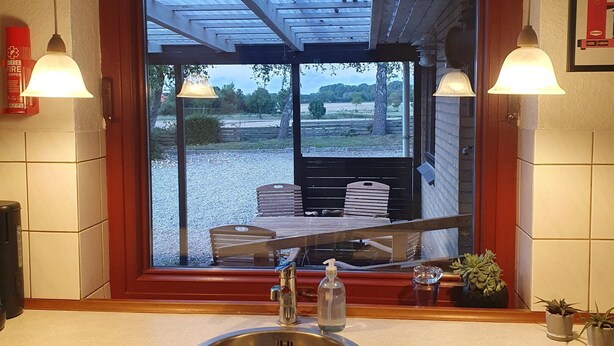 Een keuken met een groot raam, een spoelbak en twee wandlampen.