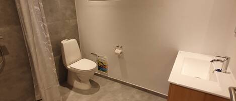 A modern bathroom with a toilet, a window, a sink, and a shower area.