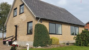 Een tweelaags huis met een schuin dak, een bakstenen gevel en een verzorgd gazon.