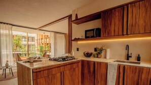 Uma cozinha moderna com armários de madeira, micro-ondas embutido e uma janela grande com cortinas.
