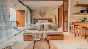 Quarto moderno com cama, mesas de cabeceira, um laptop e vista para o exterior.