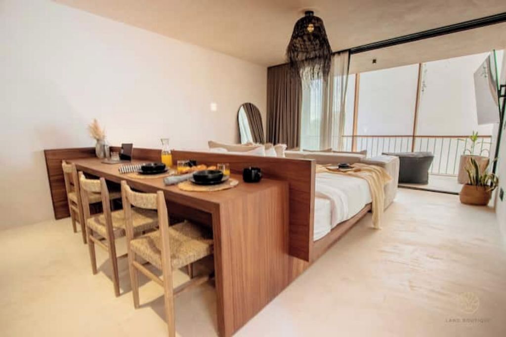 A modern hotel room with a wooden desk, a bed, and a large window offering a view.