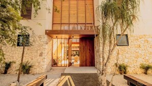 Un edificio moderno con fachada de piedra, ventanas con listones de madera y una entrada central.