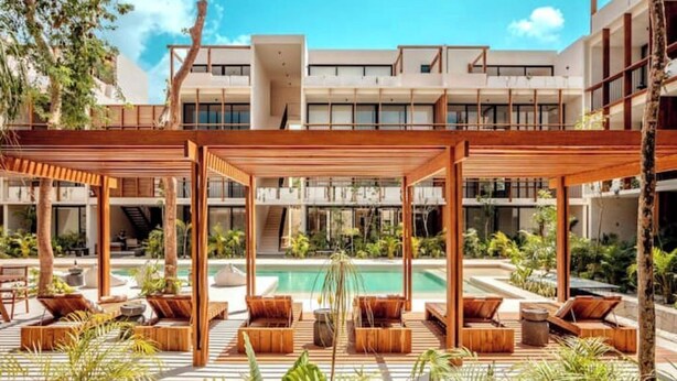 Ein moderner Poolbereich im Freien mit Holz-Pergolen, Liegestühlen und freiem Blick auf ein Schwimmbecken.