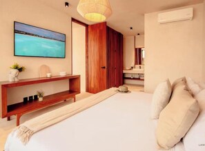 Een moderne slaapkamer met een groot bed, een houten garderobe en een tv met daarop een strandbeeld.