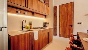 Una cucina moderna con mobili in legno, un frigorifero in acciaio inossidabile, un lavello e un'area pranzo con tavolo e sedie.