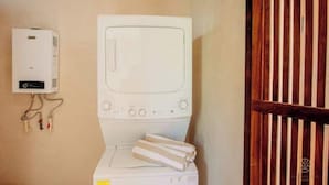 Una stanza con una lavatrice bianca, una porta in legno e un termosifone a parete.