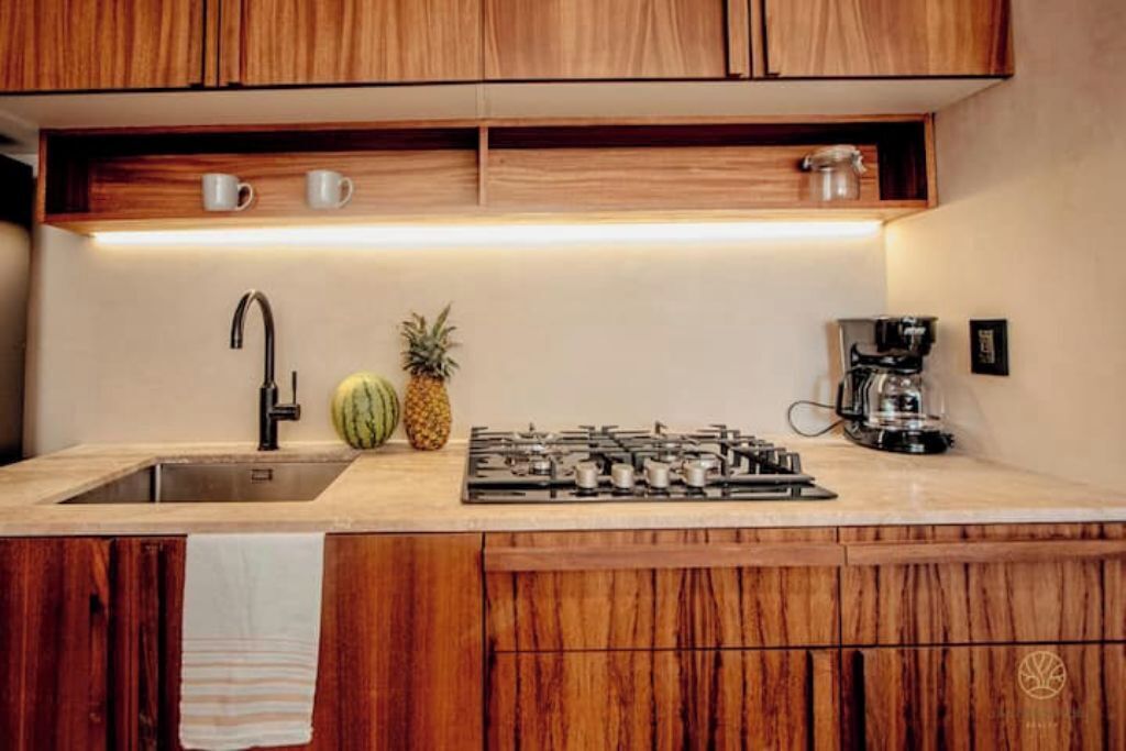 Une cuisine avec des meubles en bois, un évier en acier inoxydable, une cuisinière à gaz et une machine à café.
