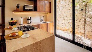 A modern kitchen with a gas stove, coffee maker, and a stone wall visible through the window. - Spacious high-end apt w/ private pool (Tulum)