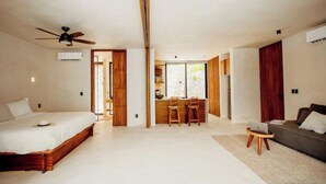 A modern bedroom with a large bed, a small desk, and a sofa. - Spacious high-end apt w/ private pool (Tulum)