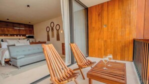 Uma sala de estar moderna com um sofá, duas cadeiras de madeira e uma mesa com copos.