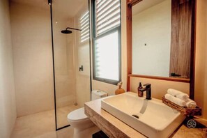 Ein modernes Badezimmer mit Duschkabine aus Glas, einem weißen Waschbecken mit Holzablage und einem großen Spiegel darüber.