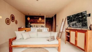 Un soggiorno moderno con un divano in legno, una zona pranzo con un mobile in legno e una cucina sullo sfondo.