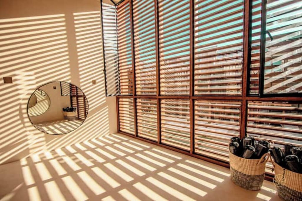 A room with a geometric patterned wall, a circular mirror, and a woven basket with items on the floor.