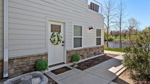 A two-story house with a front porch, a stone foundation, and a small garden area. - Sheboygan Riverside Condo (Sheboygan)