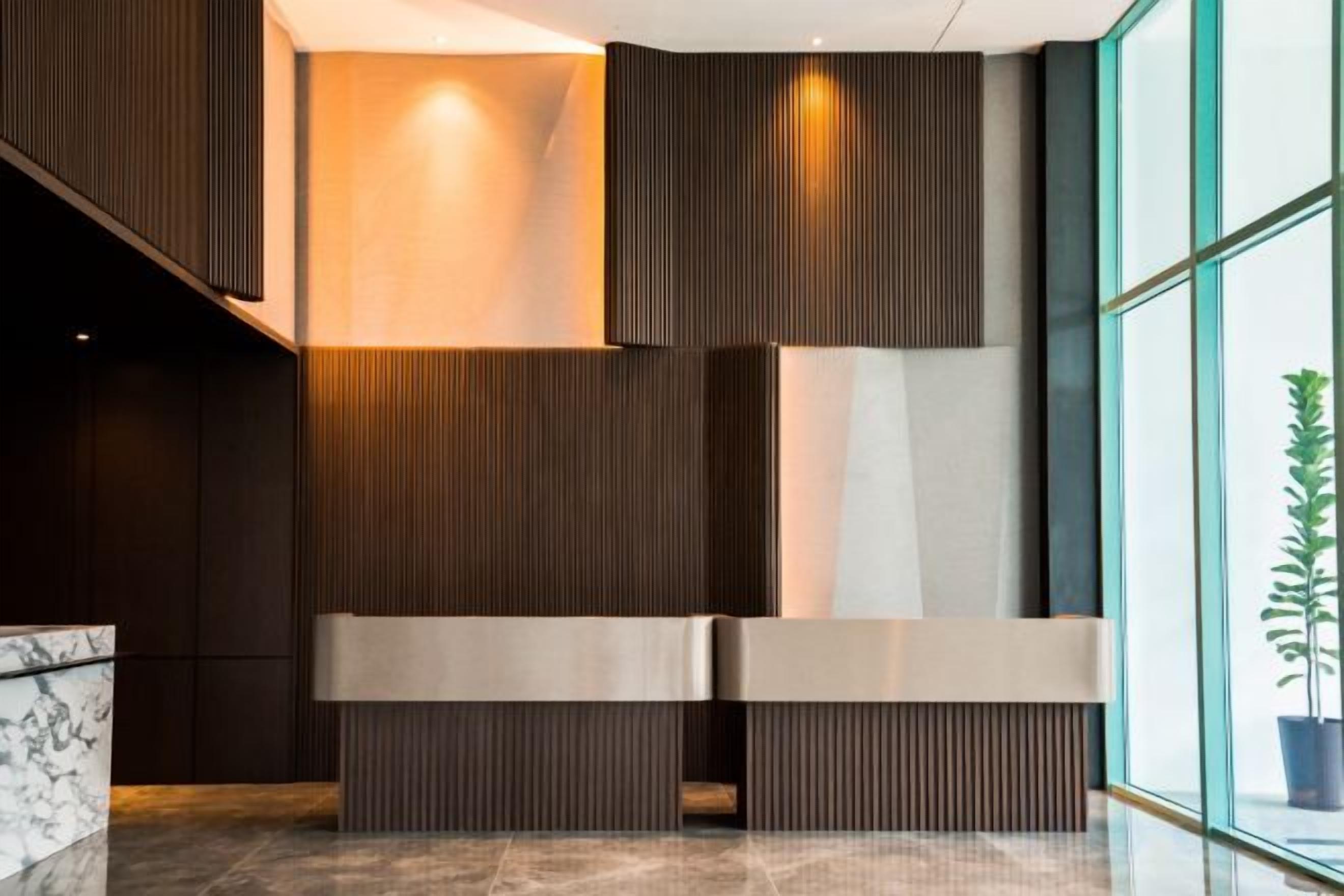 A reception area with a modern design, featuring a reception desk, a potted plant, and a large window.