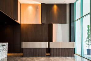 A reception area with a modern design, featuring a reception desk, a potted plant, and a large window. - Liwan, Baysuite by Ayuhouz (Kota Kinabalu)