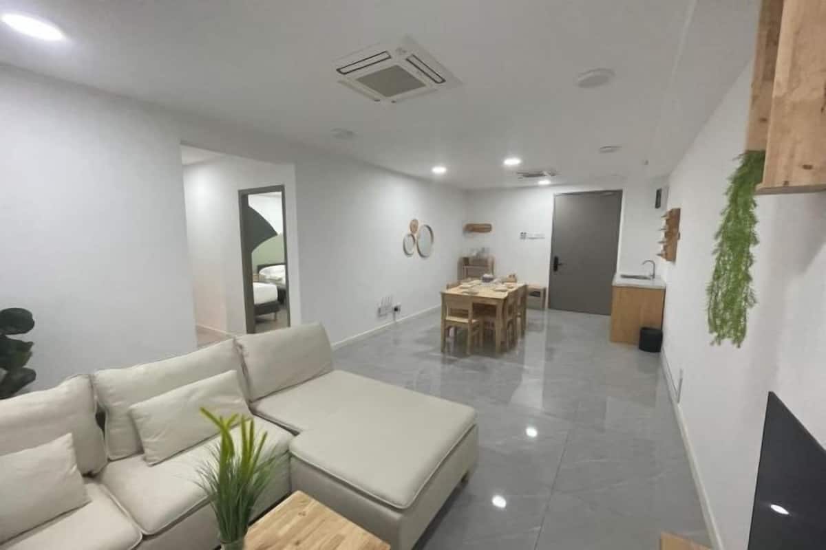 A modern living room with a sofa, a coffee table, and a dining area with a table and chairs.