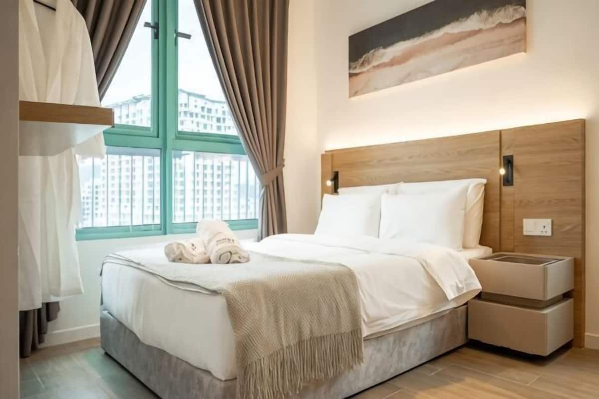 A hotel room with a bed, bedside table, and a window with curtains.
