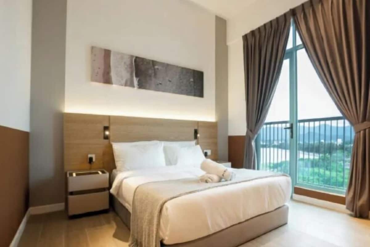 A hotel room with a large bed, a nightstand, a wall-mounted artwork, and a view through a large window.
