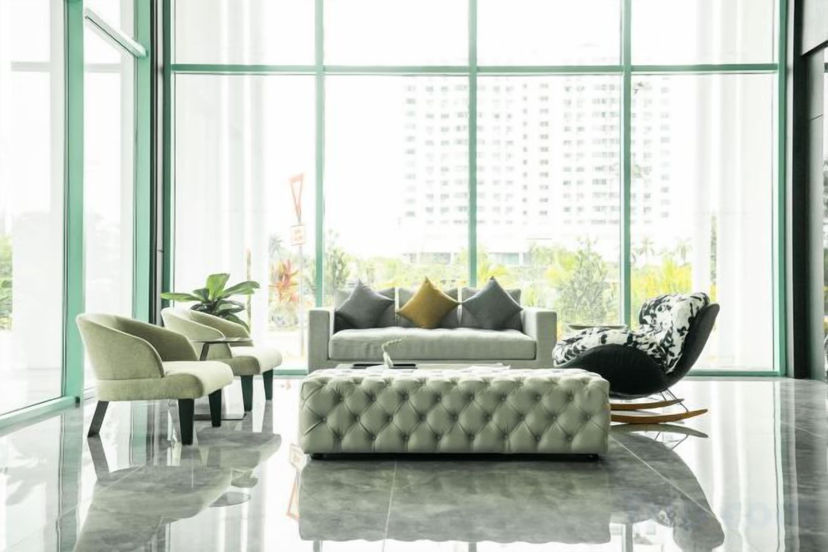 A modern living room with a sofa, chairs, and a glass wall.